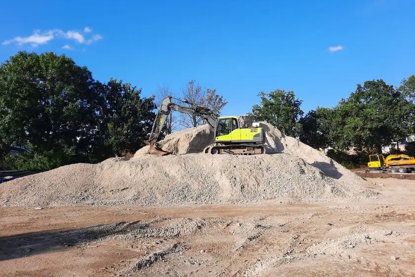 Excavator on a graded dirt pile at a construction site