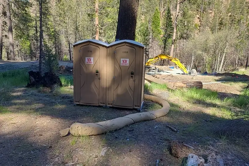 Two portable restroom units placed at a work site with erosion control matting beneath them